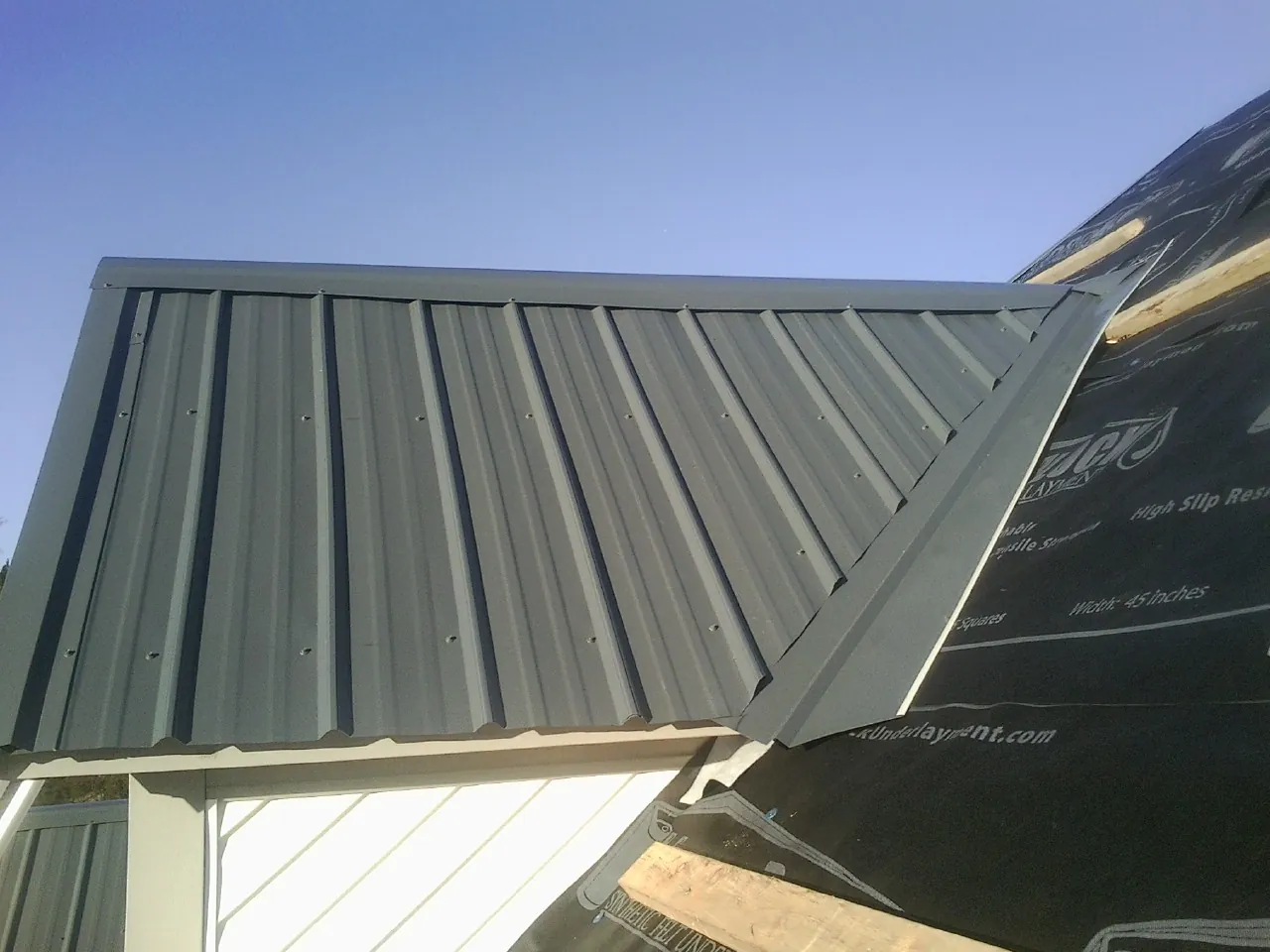 Gray metal roof panels going on over a garage gable in Groves
