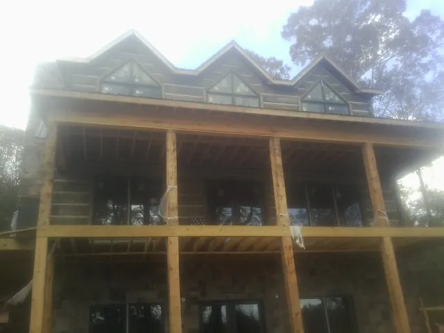 Dormers and porch framing on a large log home under construction — Roof Coating work by our crew in Groves
