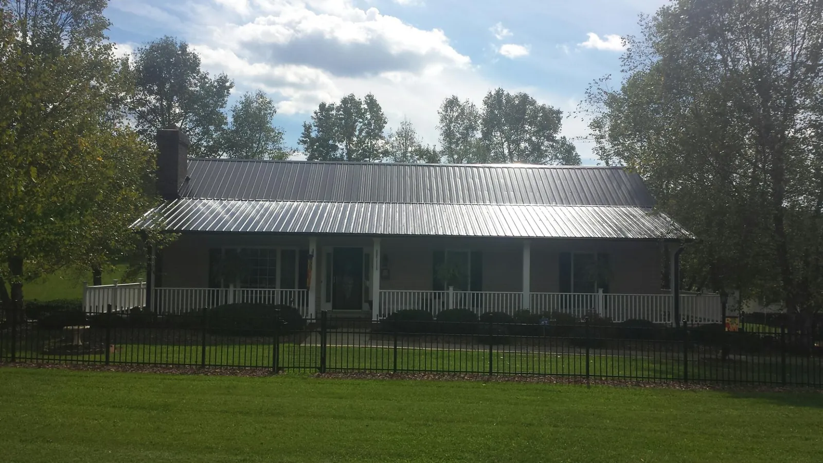 Gray metal roof on a brick ranch with a full width front porch — Gutter Guard Installation work by our crew in Groves
