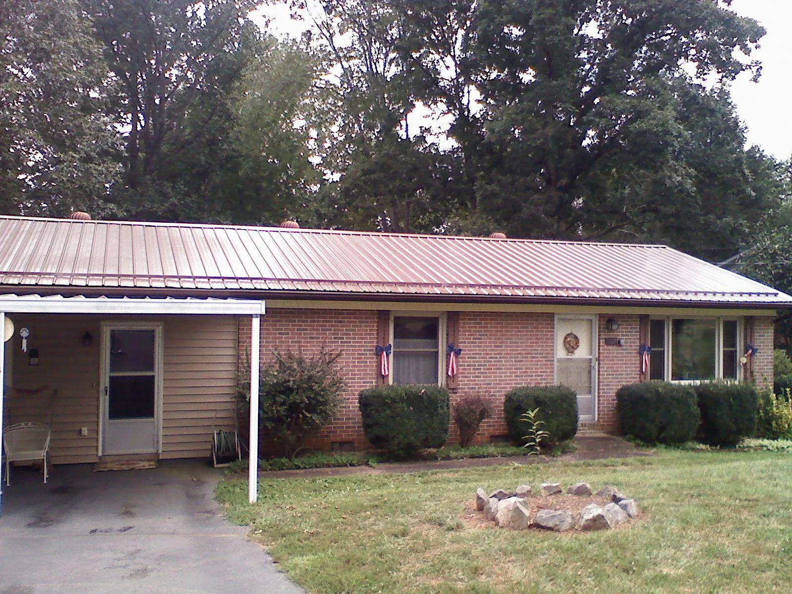 Bronze metal roof and carport on a brick ranch home — Roof Repair work by our crew in Groves