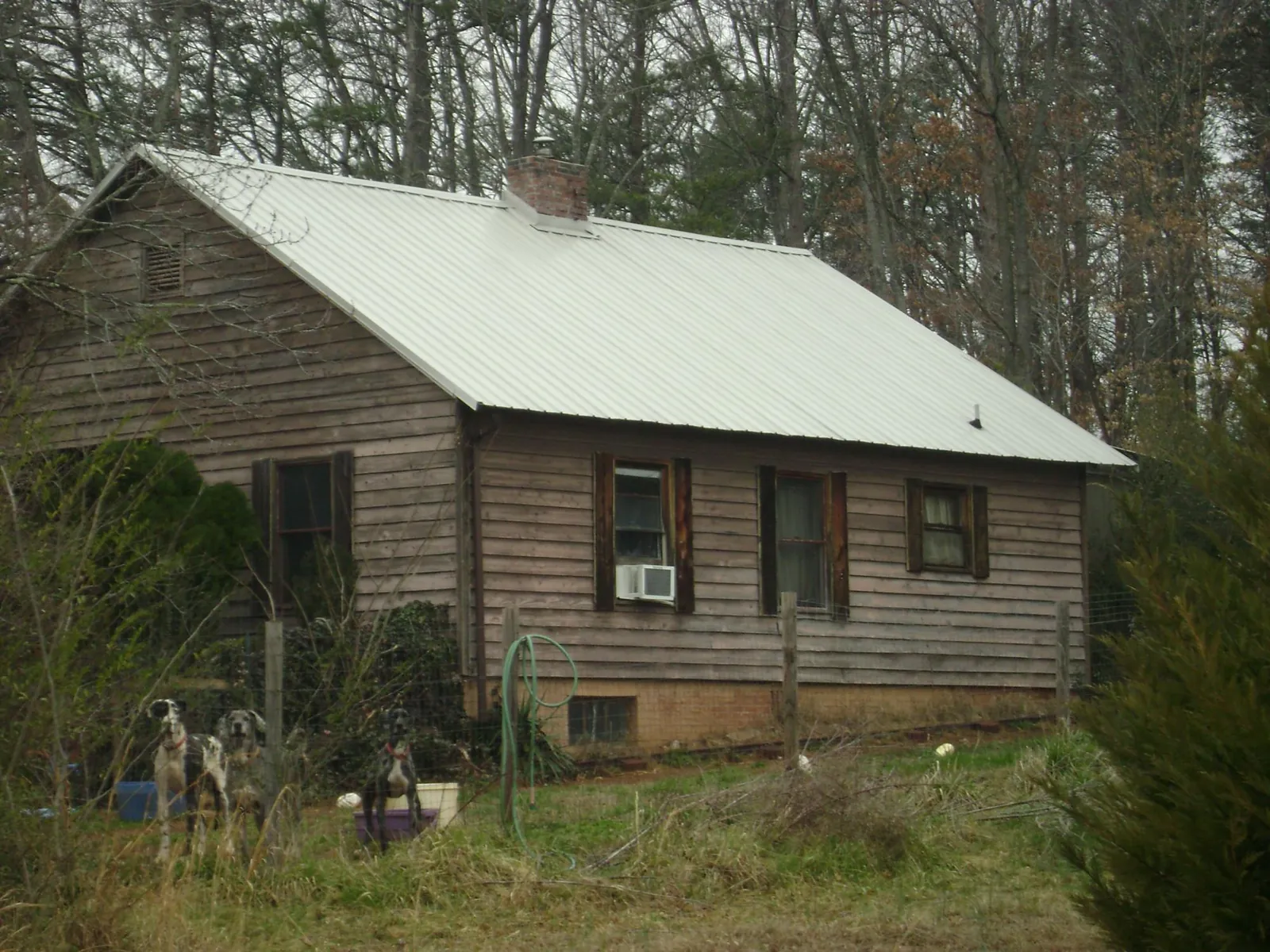 White metal roof on an old wood sided farmhouse, from a Metal Roof Installation job in Groves